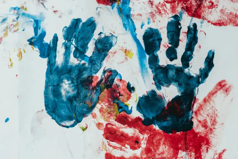 Manos de niños pintadas con colores vibrantes en un taller creativo