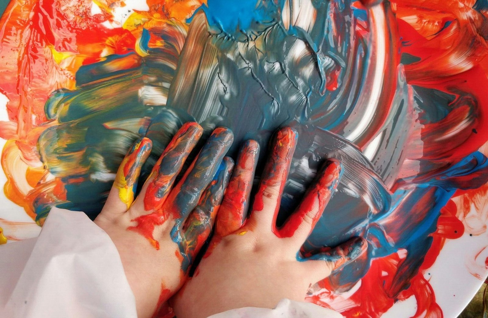 Manos de niños mezclando pintura de colores durante una actividad creativa y educativa